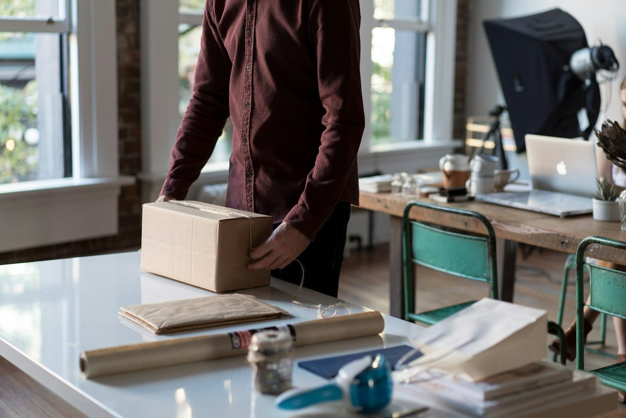 Personne refermant un carton d’expédition sur une table de travail