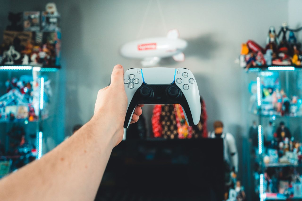 Manette prise en main devant une vitrine de jeux éclairée